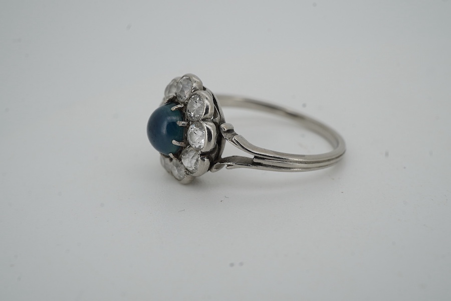 A sapphire and diamond cluster ring, early 20th century, set with a cabochon sapphire measuring approximately 5 x 5 x 3mm, within a border of circular-cut diamonds totalling approximately 0.90 carats, size M, gross weigh